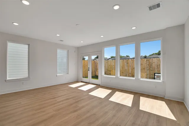 a view of an empty room with a window and wooden floor