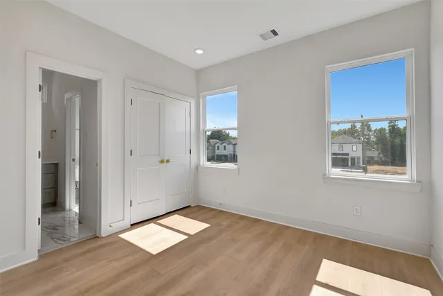 a view of empty room with wooden floor and fan