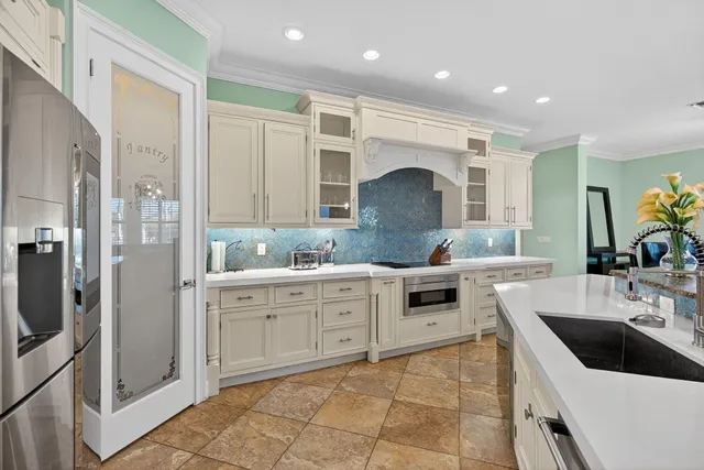 a large white kitchen with a large counter top stainless steel appliances and cabinets