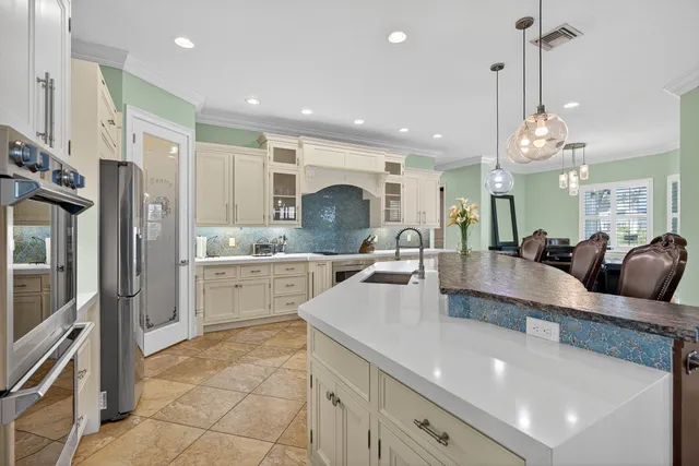 a large kitchen with granite countertop a large counter top a sink stainless steel appliances and cabinets