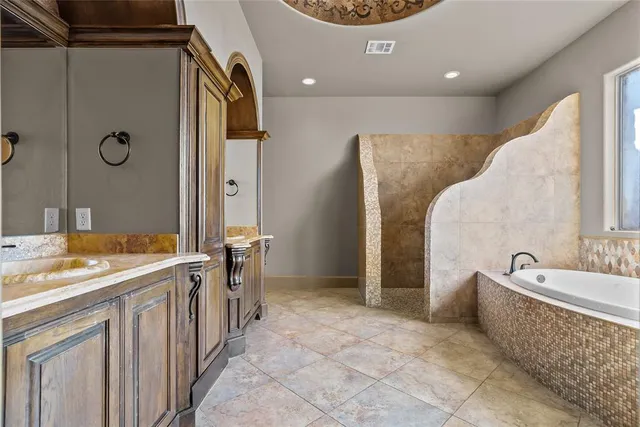 a spacious bathroom with a tub sink and mirror