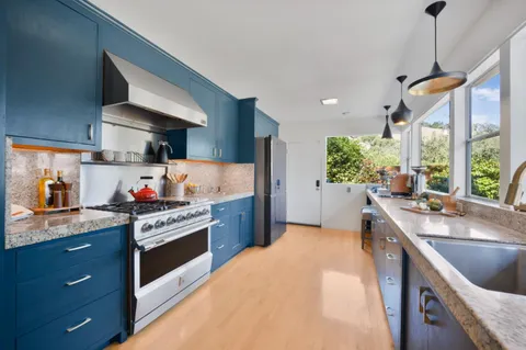 a kitchen with stainless steel appliances granite countertop a sink a stove and a wooden floors