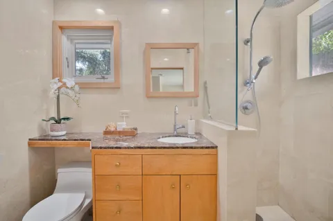 a bathroom with a granite countertop toilet sink and mirror