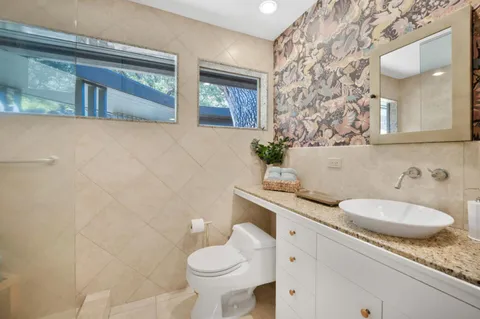 a bathroom with a granite countertop sink mirror and toilet