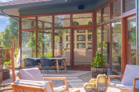 a view of a patio with couches chairs potted plants and floor to ceiling window