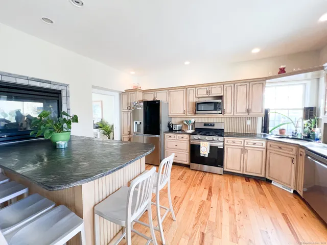 a kitchen with stainless steel appliances granite countertop a stove a sink dishwasher a microwave oven with a dining table and chairs