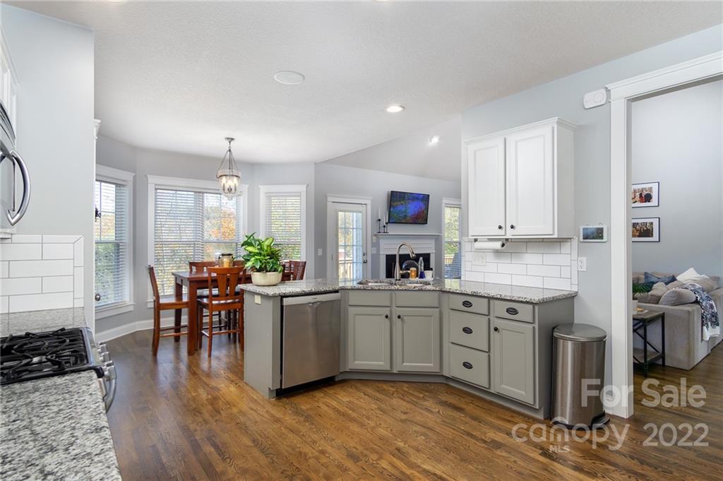 225 Nut Hatch Loop Arden, NC 28704 - Photo 13 of 48 a kitchen with stainless steel appliances granite countertop a stove top oven a sink dishwasher and white cabinets with wooden floor