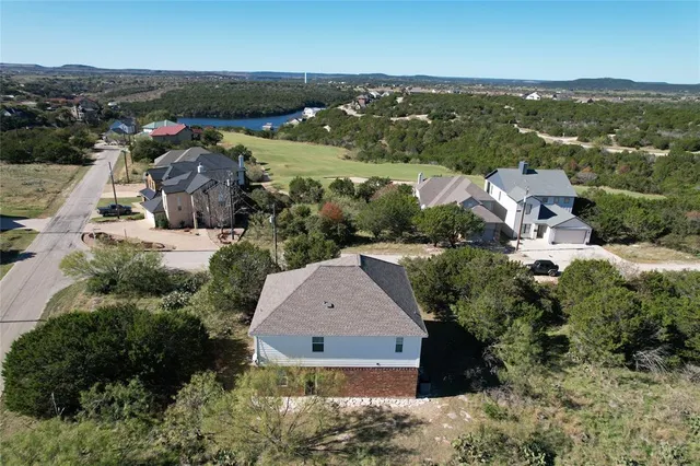 an aerial view of residential houses with outdoor space and trees