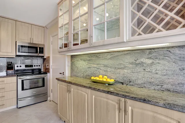 a kitchen with stainless steel appliances granite countertop a refrigerator sink and white cabinets