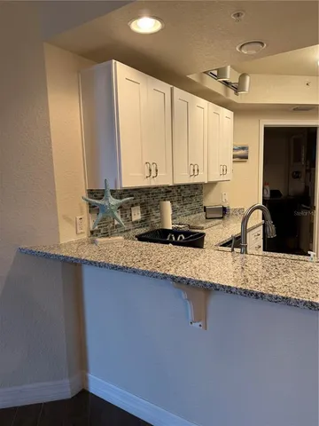 a kitchen with stainless steel appliances kitchen island granite countertop a refrigerator a stove and a sink