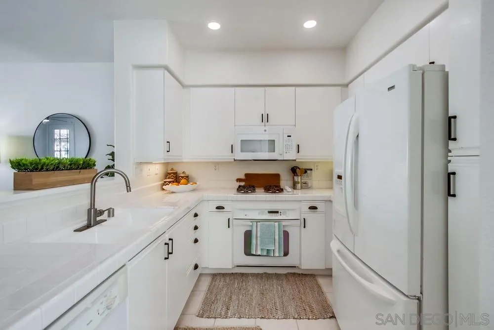 12490 Heatherton Court, Unit 10 San Diego, CA 92128 - Photo 23 of 39 a kitchen with white cabinets and refrigerator