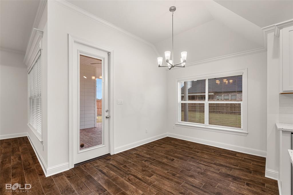 304 Prien Lk Loop Bossier City, LA 71111 - Photo 22 of 39 Dining area featuring wood-finish flooring, a vaulted ceiling, and a contemporary chandelier