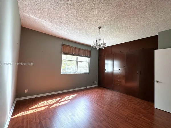 a view of empty room with wooden floor and window