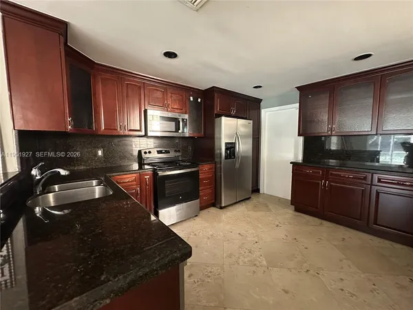 a kitchen with granite countertop stainless steel appliances and wooden cabinets