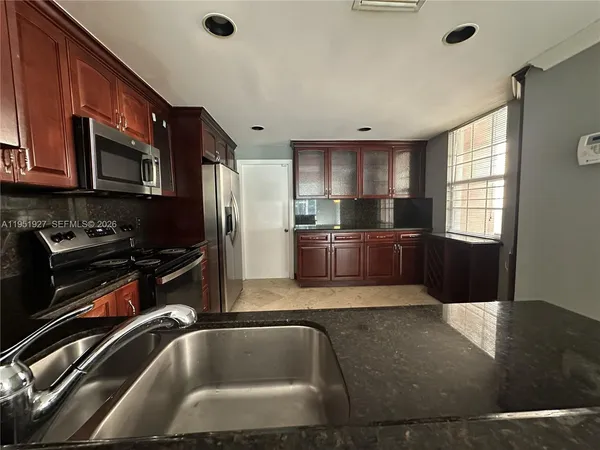 a kitchen with stainless steel appliances granite countertop a sink a stove and a refrigerator