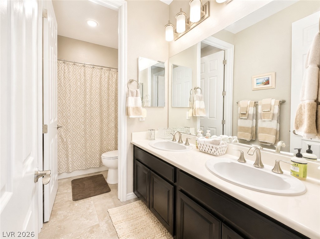 9724 University Ridge Avenue Las Vegas, NV 89149 - Photo 54 of 61 Dual vanities complement a functional bathroom with bright overhead lighting.