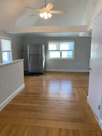 a view of empty room with wooden floor and fan