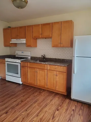 a kitchen with wooden floors and white cabinets