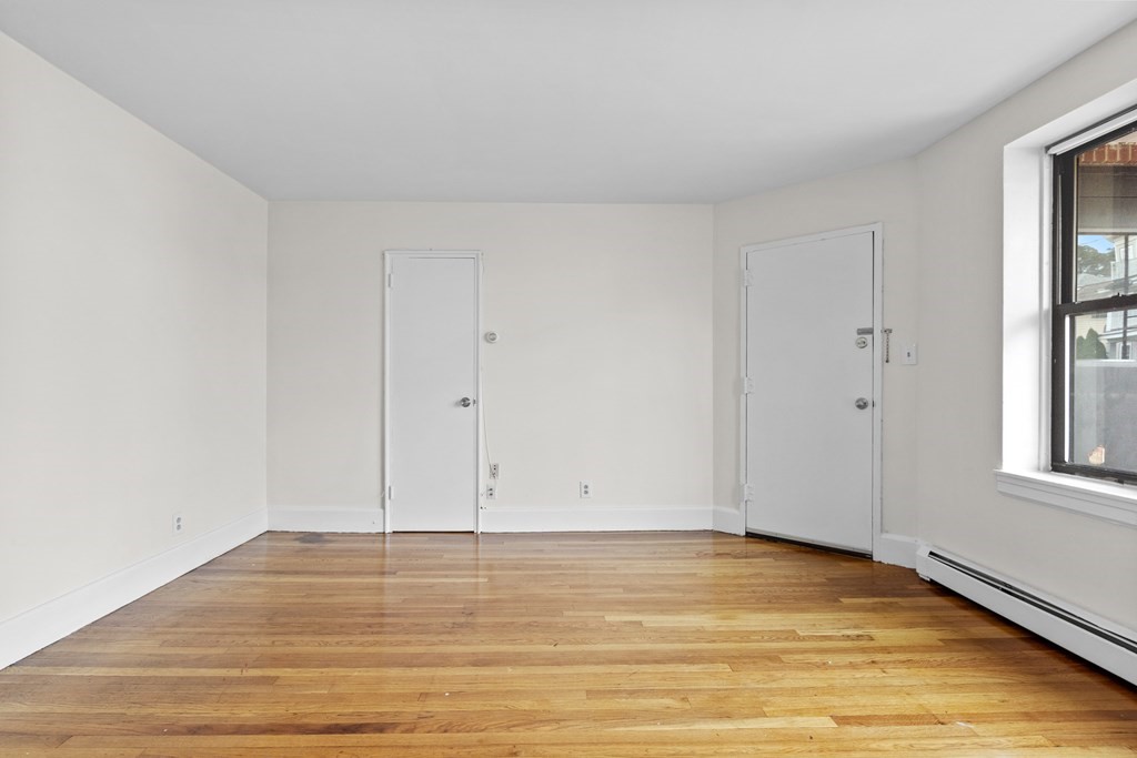 11 Victory Road, Unit 27 Boston, MA 02122 - Photo 12 of 16 a view of an empty room with wooden floor and a window