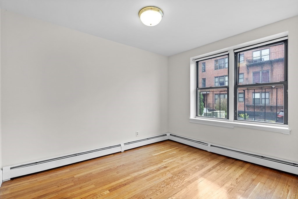 11 Victory Road, Unit 27 Boston, MA 02122 - Photo 9 of 16 an empty room with wooden floor and windows