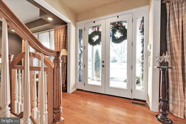 a kitchen with stainless steel appliances granite countertop a sink a stove a refrigerator and white cabinets with wooden floor