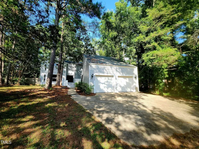a view of a house with large tree and covered with wooden fence