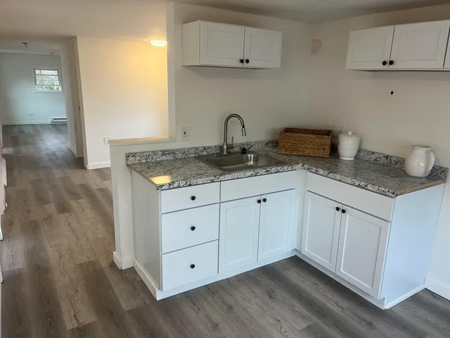 a kitchen with granite countertop white cabinets and a sink