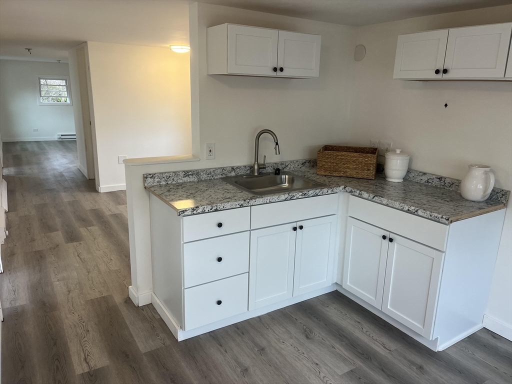 a kitchen with granite countertop white cabinets and a sink