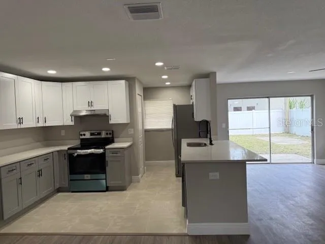 a large kitchen with stainless steel appliances granite countertop a stove a sink and a refrigerator