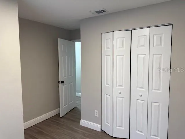 an empty room with wooden floor and closet area