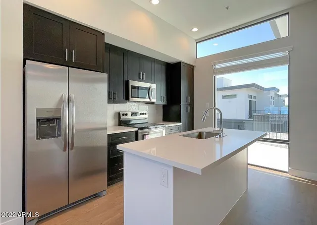 a kitchen with kitchen island a counter top space cabinets and stainless steel appliances