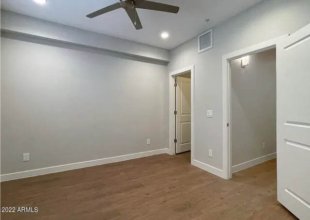 an empty room with wooden floor and closet area