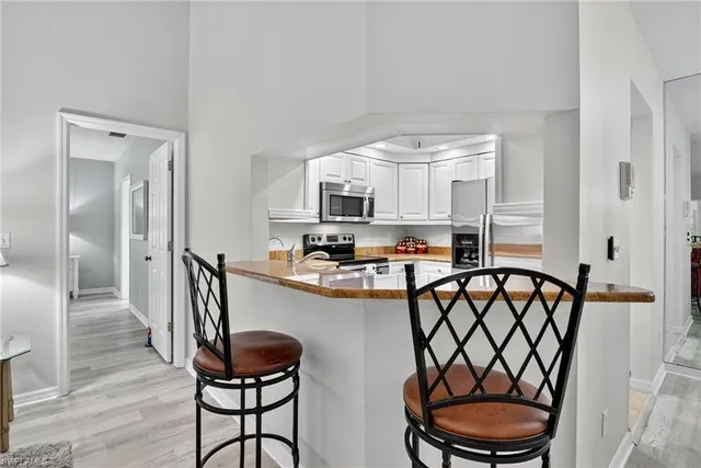 a kitchen with stainless steel appliances a dining table chairs and a refrigerator