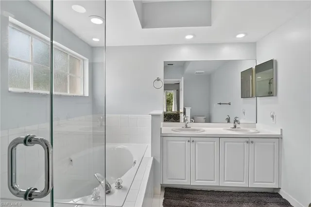 a bathroom with a double vanity sink a mirror and a bathtub