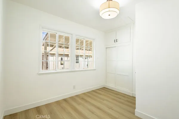 an empty room with wooden floor cabinet and windows