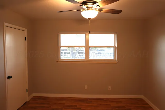 a view of a room with a large window a ceiling fan and wooden floor