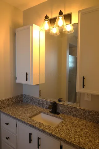 a bathroom with a granite countertop sink and a mirror