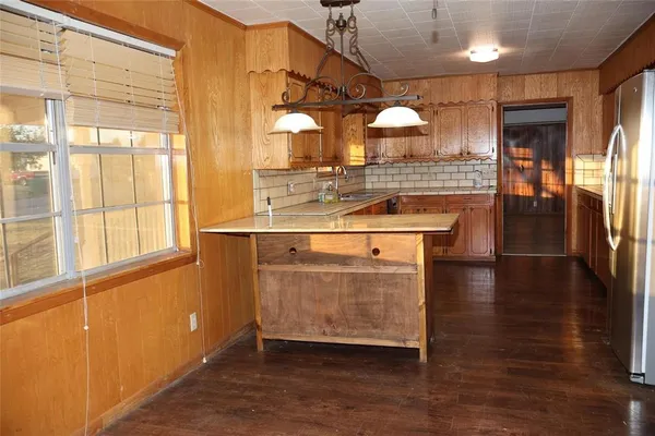 a room with stainless steel appliances kitchen island granite countertop a stove a sink and a large window