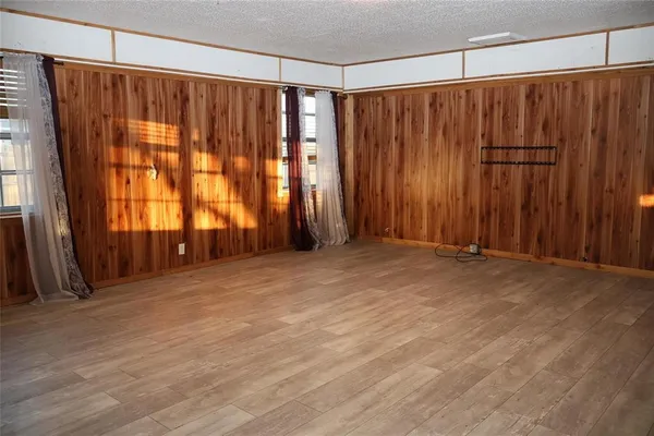 a view of an empty room with wooden walls and a window