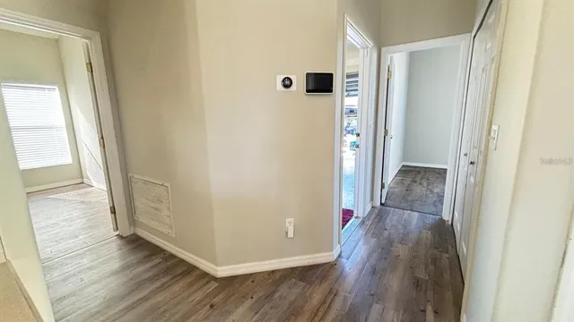 a view of a hallway with wooden floor and a bathroom