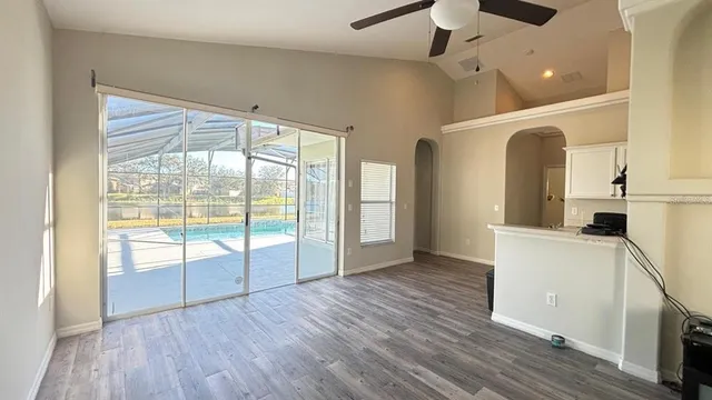 a view of empty room with wooden floor and fan