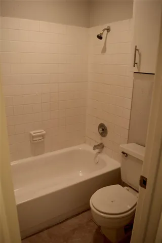 a white toilet sitting next to a bath tub and a shower