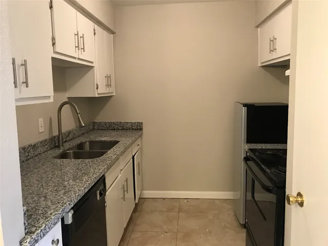 a kitchen with granite countertop a sink stove and cabinets