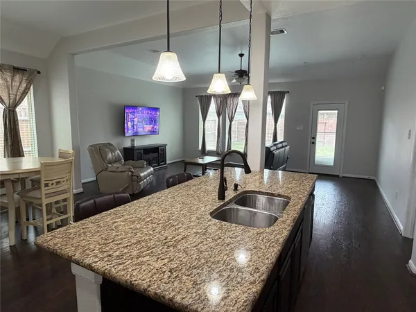 a kitchen with kitchen island granite countertop a sink a counter top space and living room view
