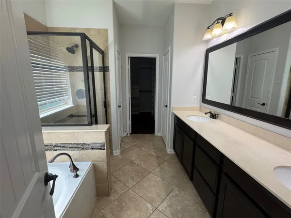 a bathroom with a double vanity sink mirror and bathtub