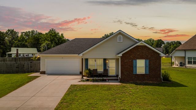 a front view of house with yard and trees in the background