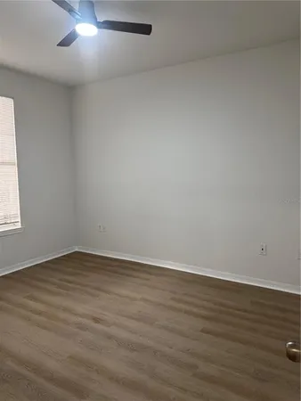 a view of an empty room with wooden floor and a window