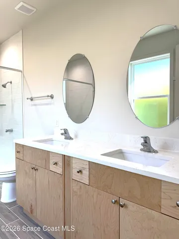 a bathroom with a sink a toilet a shower and a window