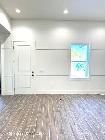 an empty room with wooden floor closet and windows