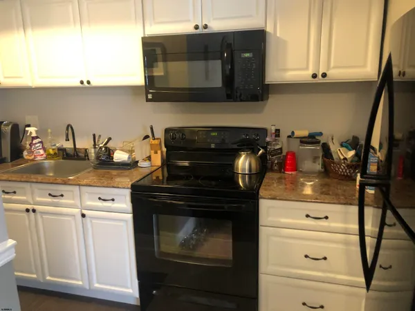 a kitchen with granite countertop white cabinets and black appliances